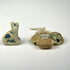 Ancient Egyptian amulet collection with seated Bastet cat and three scarabs in faience, steatite, and glazed composition.