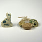 Ancient Egyptian amulet collection with seated Bastet cat and three scarabs in faience, steatite, and glazed composition.