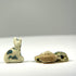 Low-angle detail of speckled green and blue cat amulet beside cluster of three scarab amulets on twine