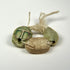 Close-up of three tied scarab amulets displaying carved grid patterns and varied green and beige stone finishes