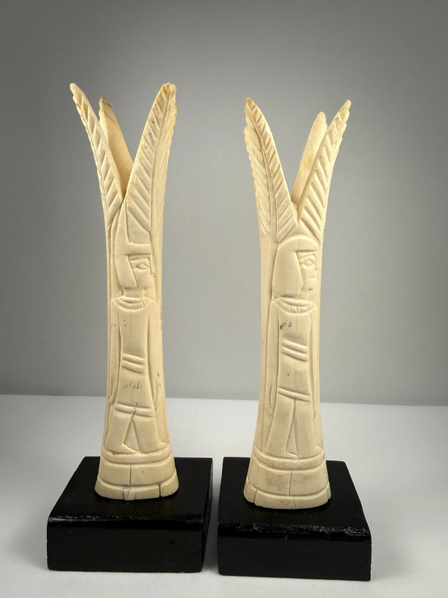 Pair of Egyptian-style carved bone candlestick holders with lotus and papyrus motifs on black display bases