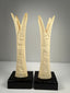 Pair of Egyptian-style carved bone candlestick holders with lotus and papyrus motifs on black display bases