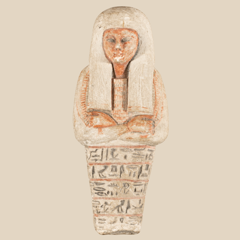Cream-coloured Egyptian-style shabti with an orange-red face, broad wig, crossed arms and rows of carved symbols.