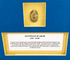 Historic Egyptian scarab amulet mounted within a recessed gold-toned display window against a deep blue background.