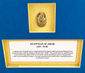 Historic Egyptian scarab amulet mounted within a recessed gold-toned display window against a deep blue background.