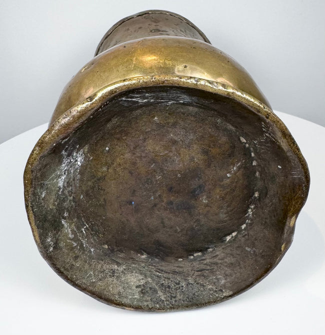 Underside of an 18th-century English brass tankard showing the circular foot and aged base with historic surface wear.