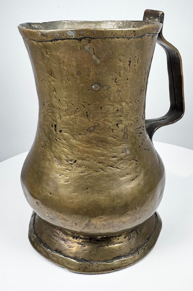 18th-century brass ale tankard displaying its curved handle, rounded body, and characteristic Georgian period construction.
