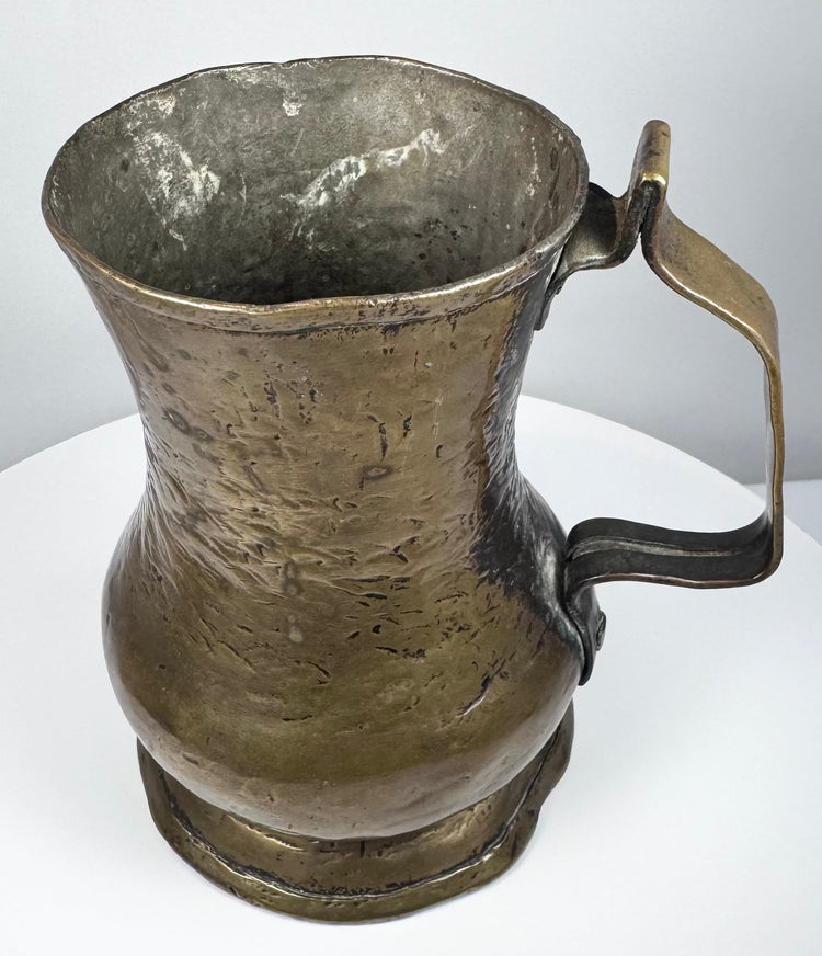 George II period brass drinking tankard with rounded baluster form, flared rim, and naturally aged surface patina.