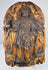 Close-up of an antique carved wooden saint with a circular halo and staff-like devotional attribute