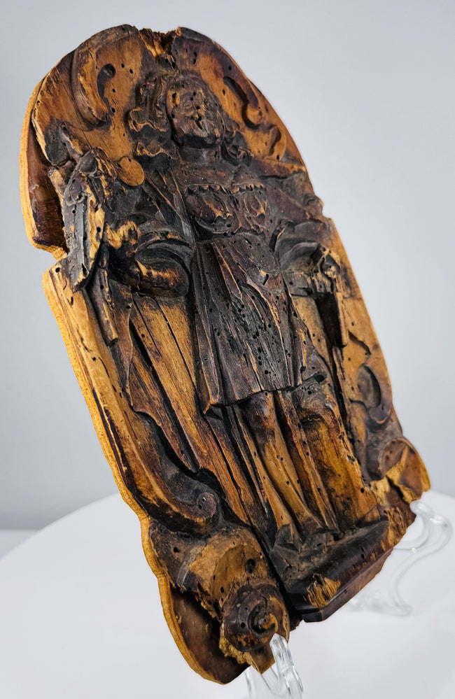 Lower section of a hand-carved devotional panel with worn robes and deeply carved cloudlike decoration