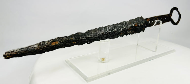 Medieval European dagger with ring pommel and corroded forged steel blade on acrylic display stand — 14th-century weapon artifact photographed on white background.