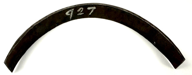 Top-down view of arched dark metal armor component displaying white painted inventory number