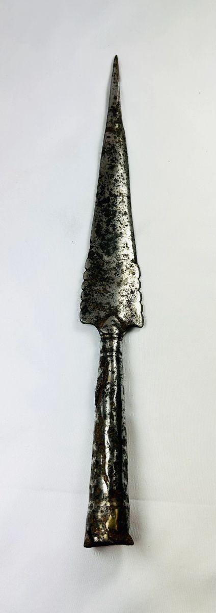 Forged iron spearhead from Europe, Iron Age to Early Medieval period (circa 1st millennium CE), featuring a scalloped-edge blade, socketed base, and historic mixed-metal brazed repair. Natural patina and surface texture reflect centuries of use, craftsmanship, and cultural significance as both a functional weapon and symbol of status.