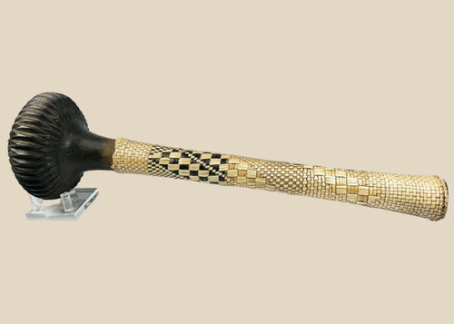 Fijian Ula throwing club with a carved dark wooden head and intricately woven light and dark fiber handle, displayed on a clear stand against a white background.