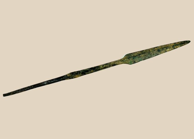 Ancient Cypriot bronze spearhead from the Early Bronze Age, Early Cypriot III period (c. 2500–1900 BCE). Leaf-shaped blade with raised central ridge, straight tang, and four-sided midsection for strength. Functional and ceremonial weapon reflecting Bronze Age metallurgy, hunting, and martial traditions in Eastern Mediterranean societies.
