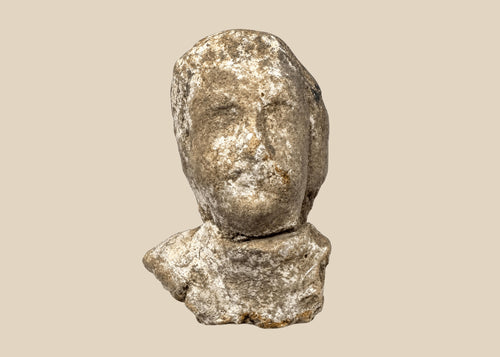 Ancient Greek terracotta protome with stylized human face, broad shoulders, and weathered pale surface
