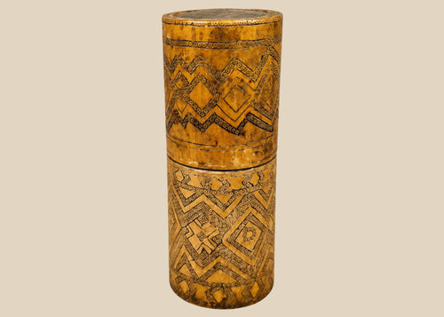 Antique carved bamboo container from Island Southeast Asia, 19th century, cylindrical with fitted lid and base, decorated with incised geometric patterns darkened with pigment, traditionally used for betel nut lime storage, photographed on a white background.