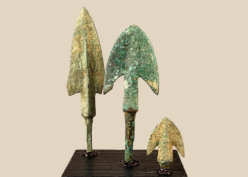 Corroded bronze historical weapon tips on dark wooden base