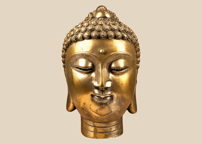 Mid-20th-century cast copper-alloy Buddha head sculpture featuring a serene expression, spiral hair curls, elongated earlobes, and a warm golden finish.