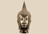 Large Thai Buddha head in Sukhothai style with serene facial features, spiral hair curls, and a tall flame-shaped finial.