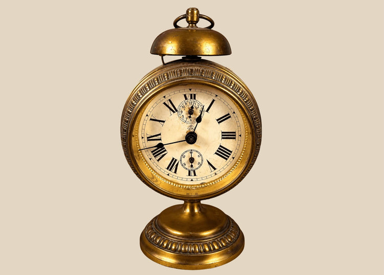 Antique German JUF brass pedestal alarm clock from circa 1900–1920, featuring an ornate circular case, Roman numeral dial, and brass bell.