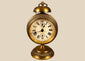 Antique German JUF brass pedestal alarm clock from circa 1900–1920, featuring an ornate circular case, Roman numeral dial, and brass bell.