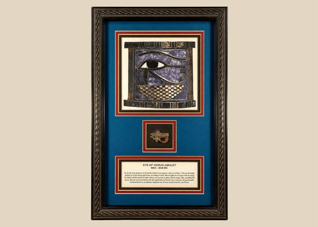 Ancient Egyptian Eye of Horus amulet dating to 663–304 BCE, mounted in an ornate framed historical display.