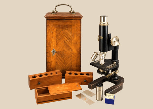 Antique Spencer Lens Company compound microscope, circa 1910–1920, displayed with its wooden carrying cabinet, accessory racks, and glass slides.