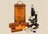Antique Spencer Lens Company compound microscope, circa 1910–1920, displayed with its wooden carrying cabinet, accessory racks, and glass slides.