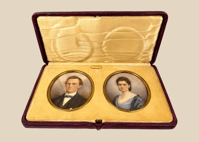 Pair of Victorian–Edwardian colour portrait miniatures of a gentleman and woman displayed in an open burgundy leather case, circa 1880–1910.