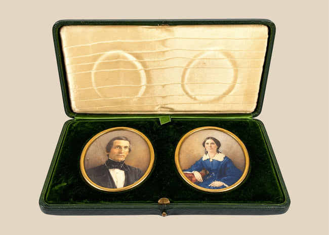 Pair of Victorian–Edwardian colour portrait miniatures of a gentleman and woman displayed in an open green velvet presentation case, circa 1880–1910.
