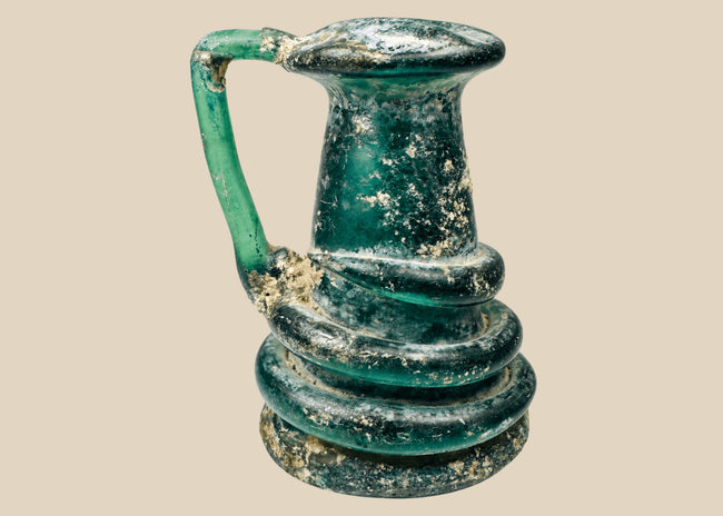 Late Roman blue-green glass jug with applied coiled trail decoration and iridescent burial patina