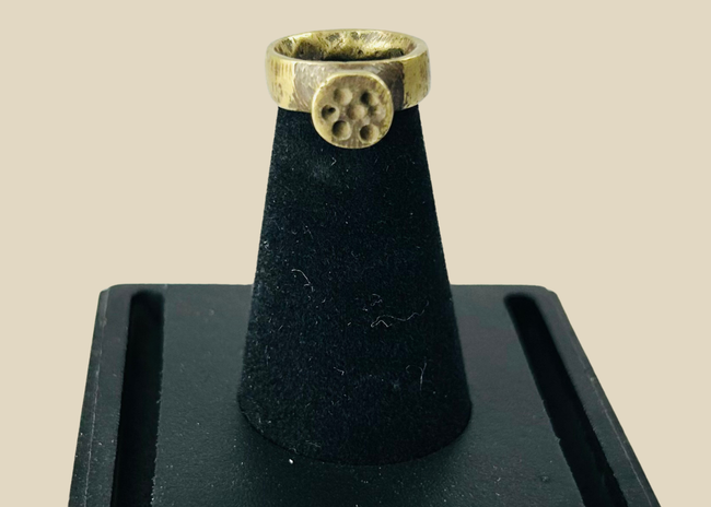Front view of ancient Roman bronze ring showing circular rosette bezel with natural green patina.