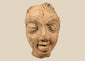 Gupta-period Northern Indian terracotta head fragment with serene almond-shaped eyes, arched brows, and softly smiling lips, warm earthen tones with mineral deposits, 3rd–5th century CE, mounted on modern display stand for preservation.
