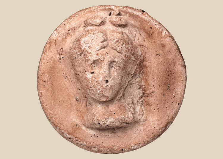 Hellenistic Greek terracotta female bust medallion with frontal portrait and aged pinkish-buff surface.