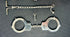 Close-up of antique 19th–20th century iron handcuffs and wrist restraints with original keys, displayed on a dark fabric background.