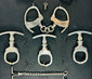 Close-up of antique 19th–20th century iron handcuffs and wrist restraints with original keys, displayed on a dark fabric background.