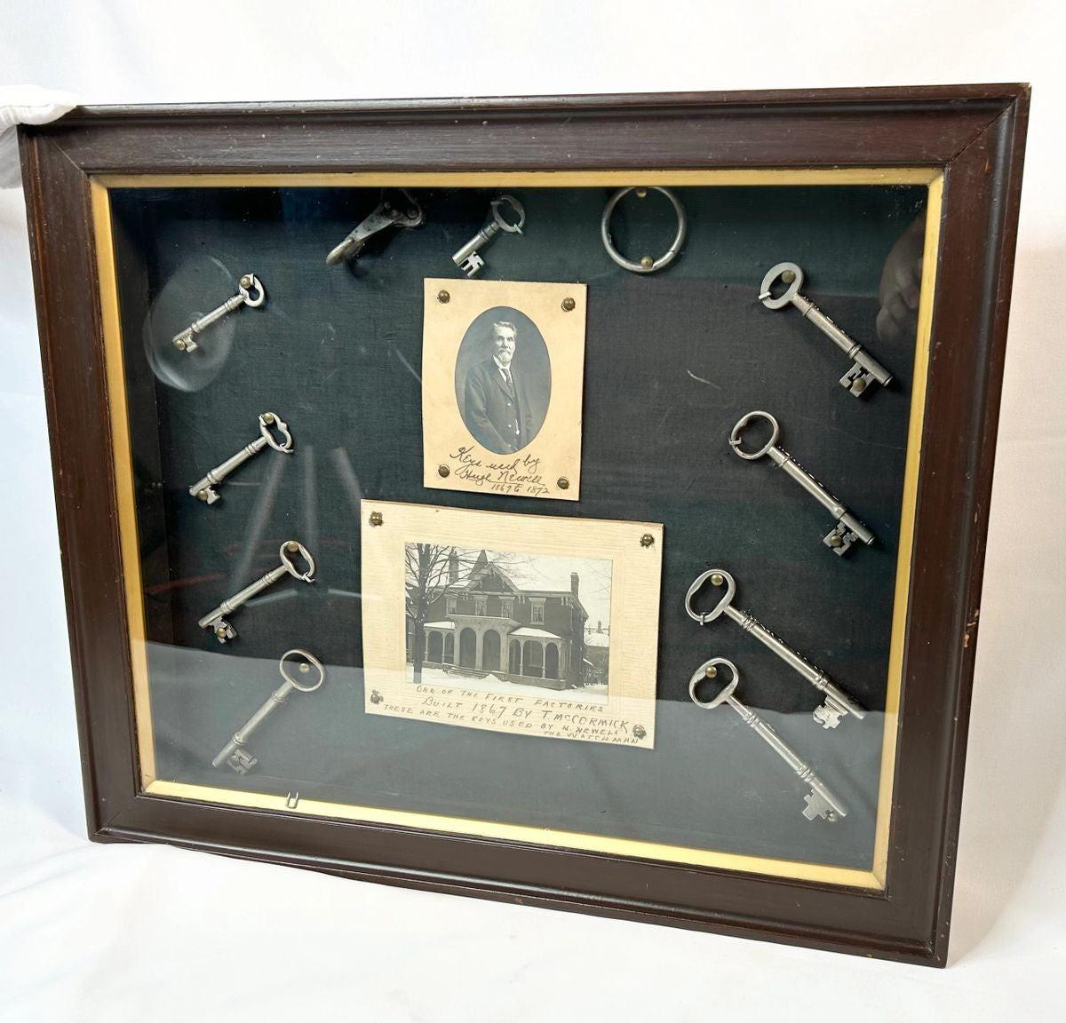 Framed 19th-century display with eleven iron keys, portrait of night watchman Hugh Newell, and early photograph of T. McCormick’s 1867 factory, preserved in a wooden shadowbox.