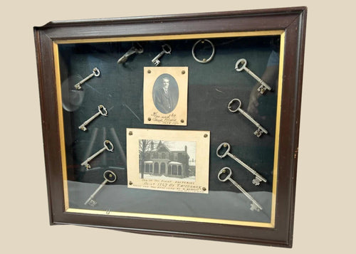 Framed 19th-century display with eleven iron keys, portrait of night watchman Hugh Newell, and early photograph of T. McCormick’s 1867 factory, preserved in a wooden shadowbox.