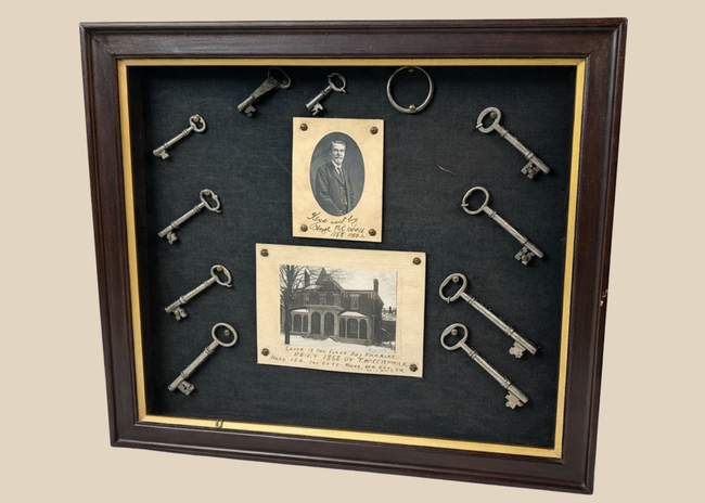 Framed 19th-century display with eleven iron keys, portrait of night watchman Hugh Newell, and early photograph of T. McCormick’s 1867 factory, preserved in a wooden shadowbox.
