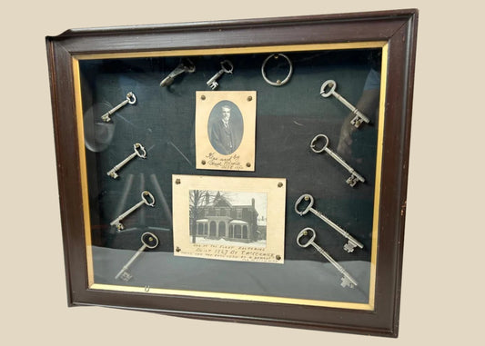 Framed 19th-century display with eleven iron keys, portrait of night watchman Hugh Newell, and early photograph of T. McCormick’s 1867 factory, preserved in a wooden shadowbox.