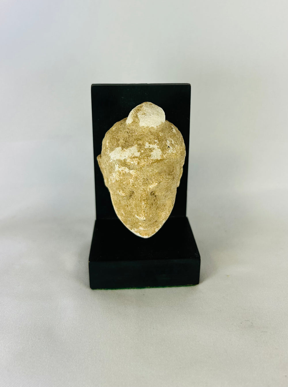 3rd–4th century CE Gandharan Buddha head carved in schist with serene expression, closed eyes, finely arched brows, and ushnisha, reflecting Greco-Buddhist Hellenistic realism and Indian spiritual iconography, mounted on modern display stand.