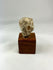 Side profile of Greco-Roman terracotta sculpture fragment mounted on a wooden display base.
