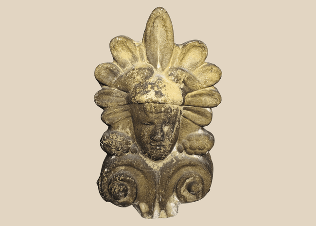 Greek terracotta architectural antefix depicting a stylized human face beneath a palmette crown, dating to the late 19th or early 20th century.