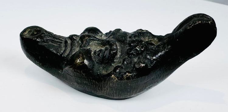 Antique cast metal oil lamp in the form of a satyr head with filling aperture and wick nozzle.
