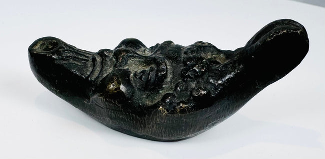 Antique cast metal oil lamp in the form of a satyr head with filling aperture and wick nozzle.