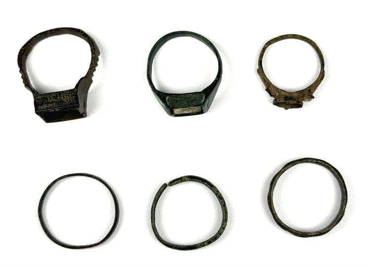 Top and front views of six ancient bronze finger rings with decorative bezels and simple bands, circa 3rd–7th century CE