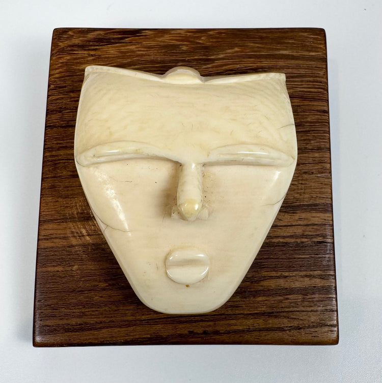 Vintage modernist bone sculpture of a serene human face, expertly carved and mounted on a square hardwood backing for wall display.