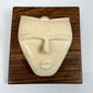 Vintage modernist bone sculpture of a serene human face, expertly carved and mounted on a square hardwood backing for wall display.