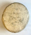 Back view of rounded stone face sculpture displayed on clear stand with natural patina